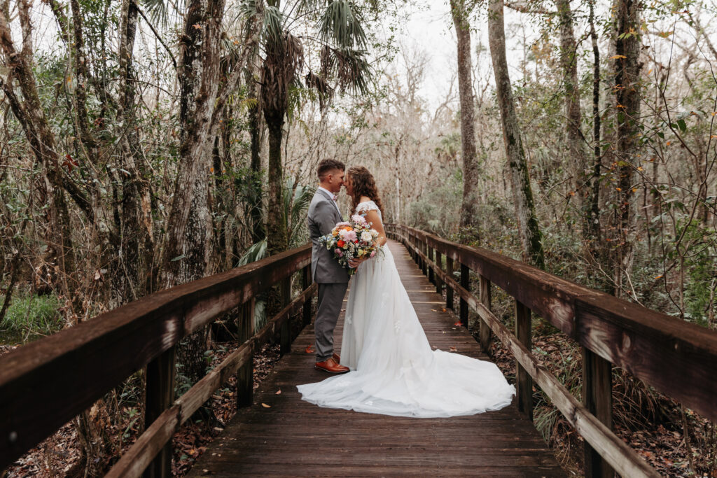 Bride and groom touching noses on a boardwalk at Highlands Hammock State Park.