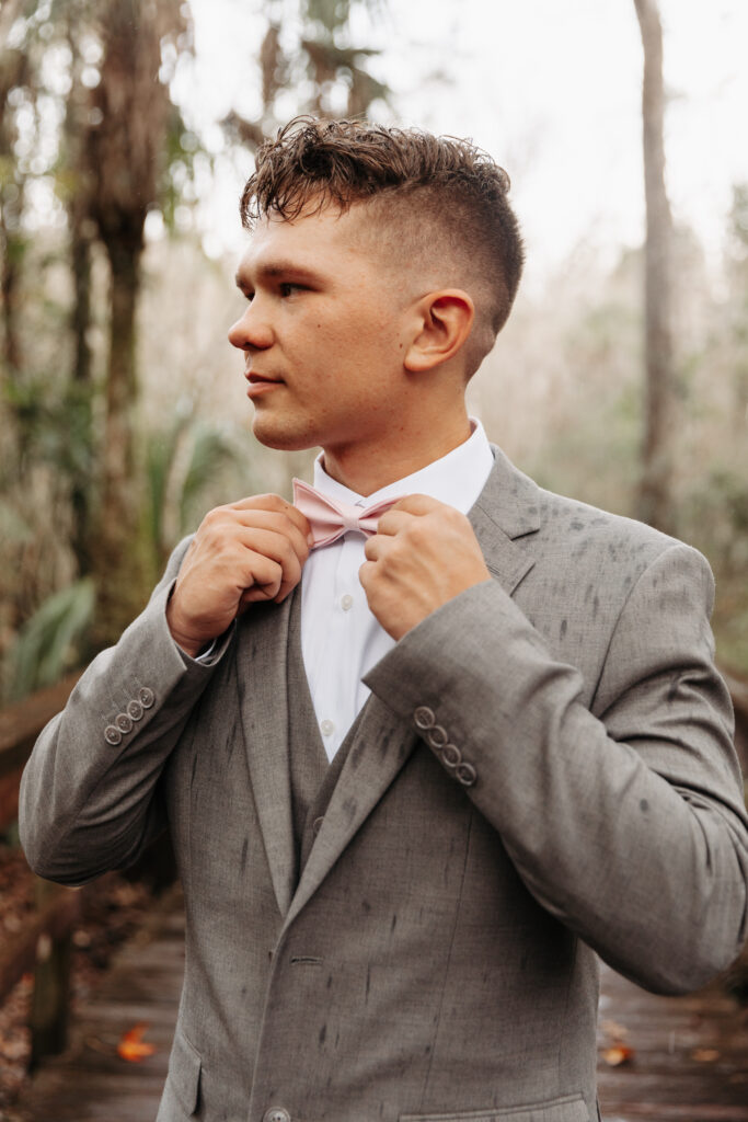 Groom in a grey suit with a pink bow tie at Highlands Hammock State Park.