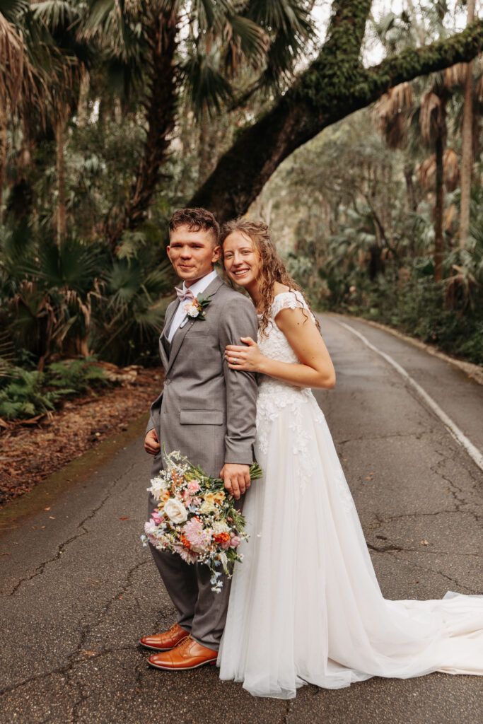 Bride hugging groom from behind at Highlands Hammock State Park.