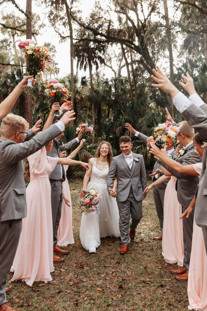 Bride and groom walking through a tunnel created by their bridal party at Highlands Hammock State Park.