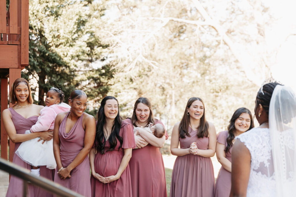 bridesmaids wearing a variety of purples having a first look with the bride