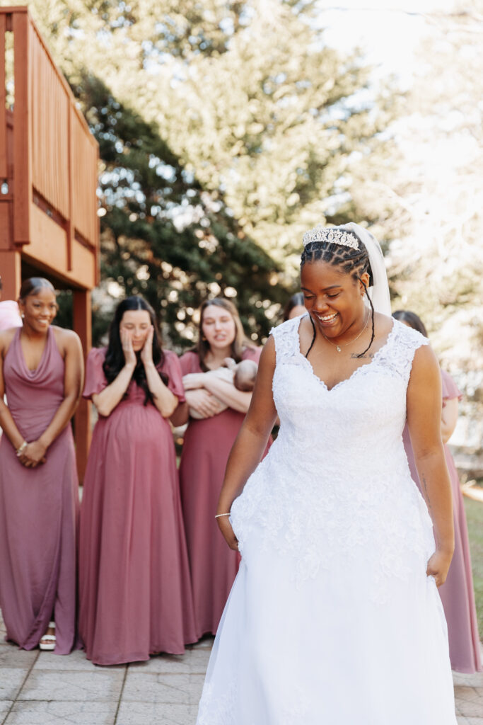 bridesmaids wearing a variety of purples having a first look with the bride