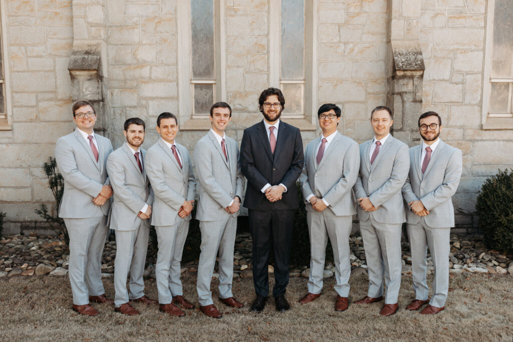 groom in a dark grey suit with his groomsmen in light grey suits