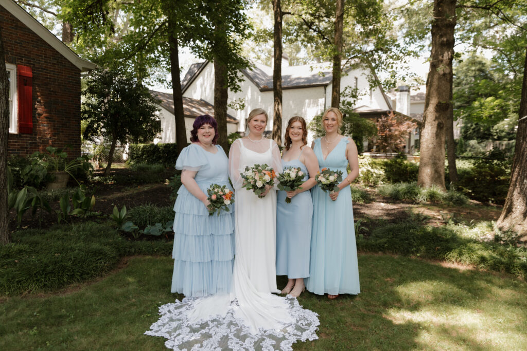 Bride with her bridesmaids wearing light blue dresses on a summer wedding day in downtown Greenville.
