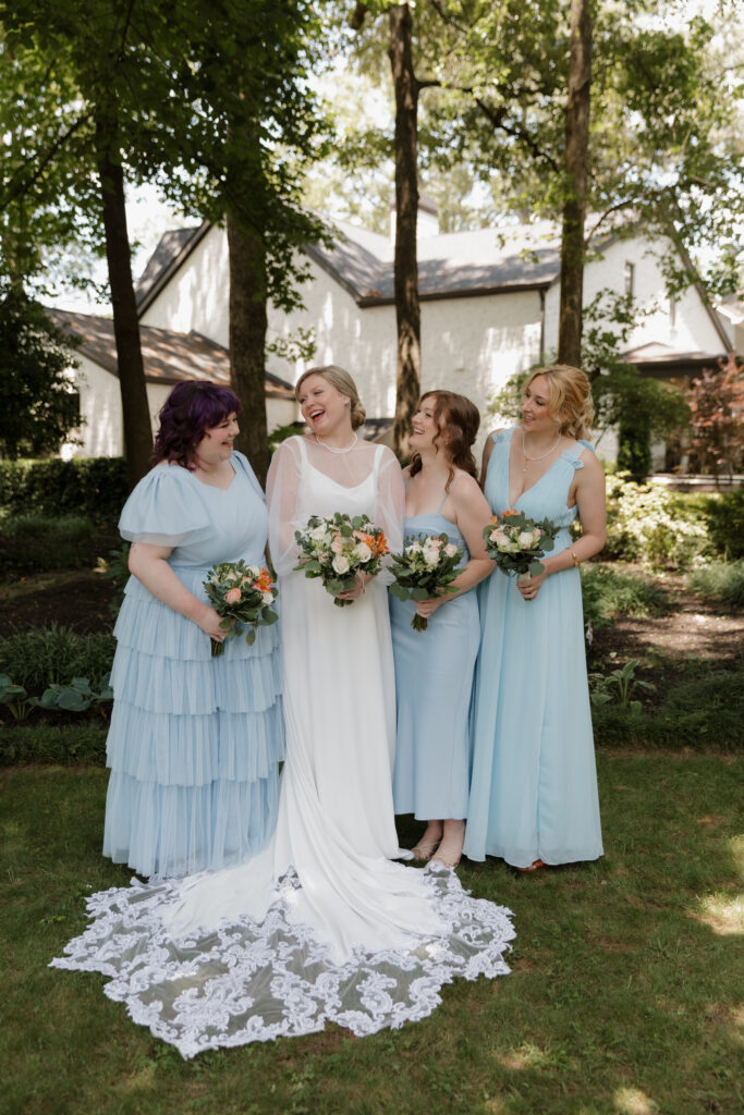Bride with her bridesmaids wearing light blue dresses on a summer wedding day in downtown Greenville.