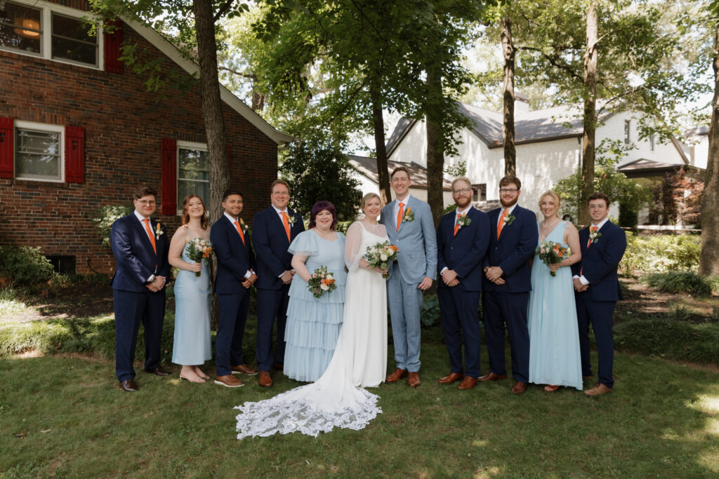 Bride and groom with their bridal party wearing blue and orange accents on a summer wedding day in downtown Greenville.