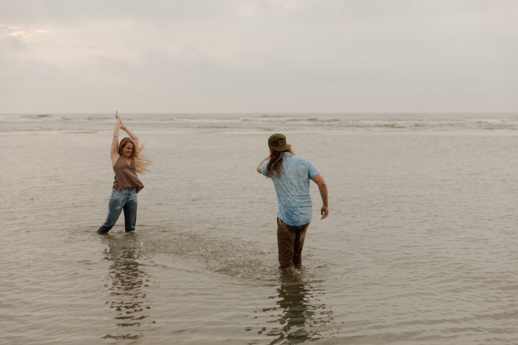 A couple playing in the ocean during their sunrise engagement session at Folly Beach in South Carolina.
