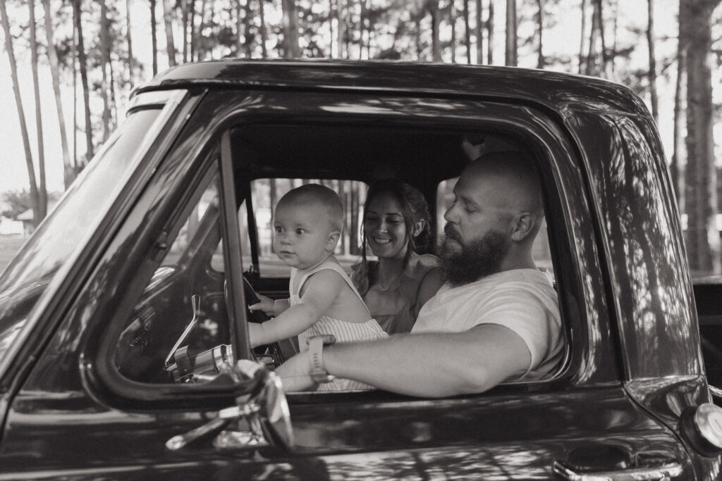 A couple with their toddler inside of a classic Ford F-150.