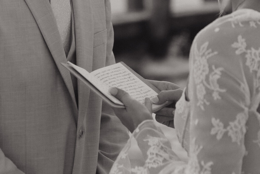 Black and white detail photo of a bride's vow book during an elopement on Folly Beach in South Carolina.