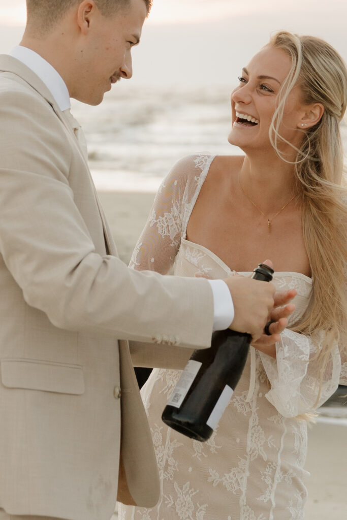 Bride and groom popping champagne during their sunrise elopement on Folly Beach in South Carolina.