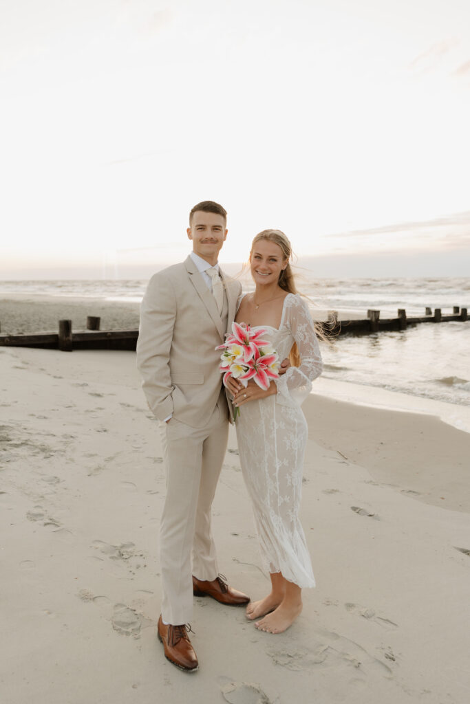 Bride and groom smiling for a portrait during their sunrise elopement on Folly Beach in South Carolina.