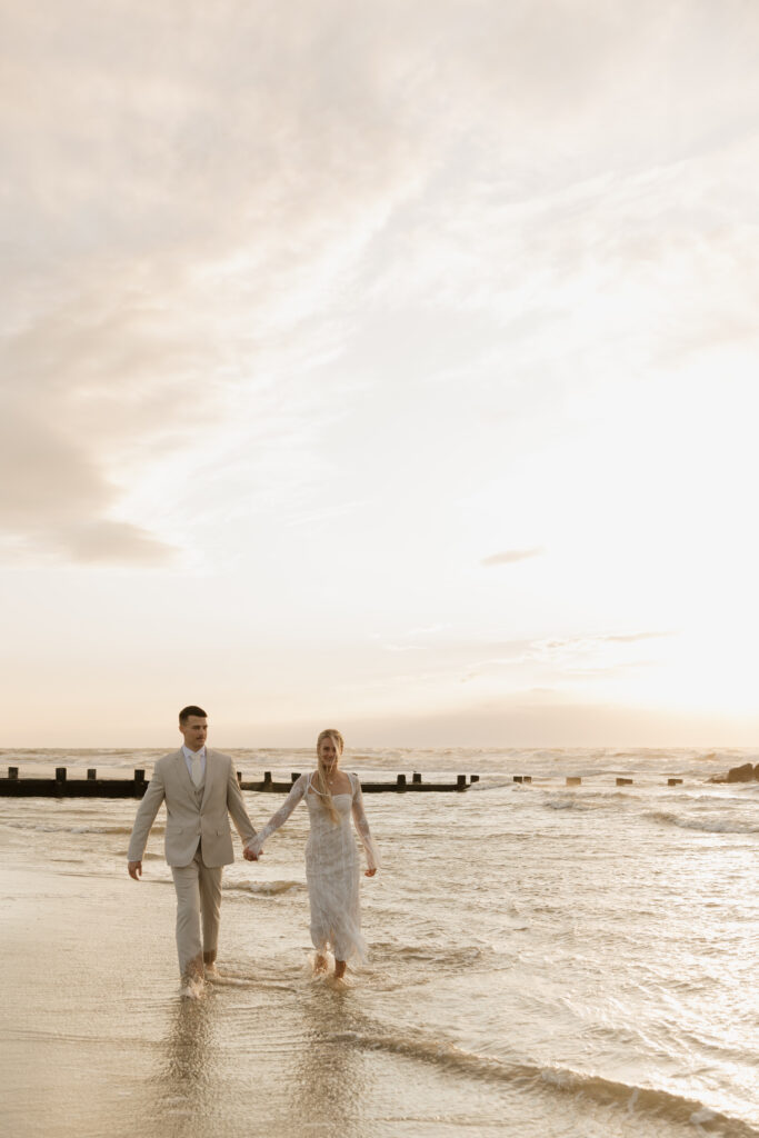 Bride and groom walking along the water during their sunrise elopement on Folly Beach in South Carolina.