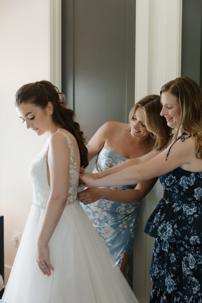 Jewish bride putting on her wedding dress with the help of her sisters.