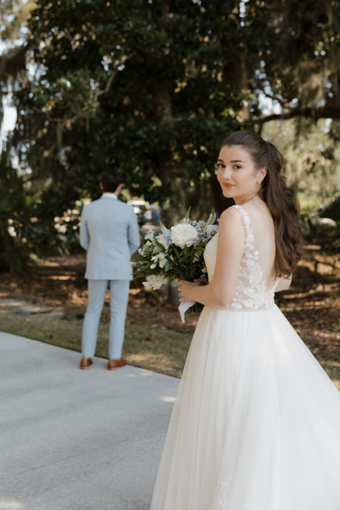Bride looking back at the camera before a first look with her groom at The Golf Club at Briar's Creek on Johns Island, SC.