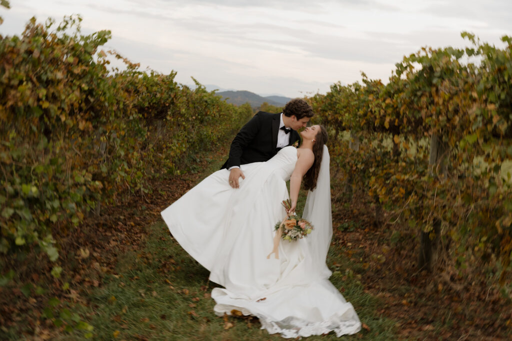Groom dipping the bride back for a kiss in the vineyard at Chattooga Belle Farm in Long Creek, SC on their fall wedding day.